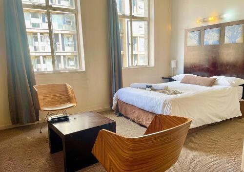 约翰内斯堡Mapungubwe Apartments的一间卧室设有一张大床和两个窗户。