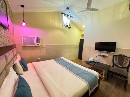 新德里Hotel Height's - Kalka ji的一间卧室配有一张床、一把椅子和电视。