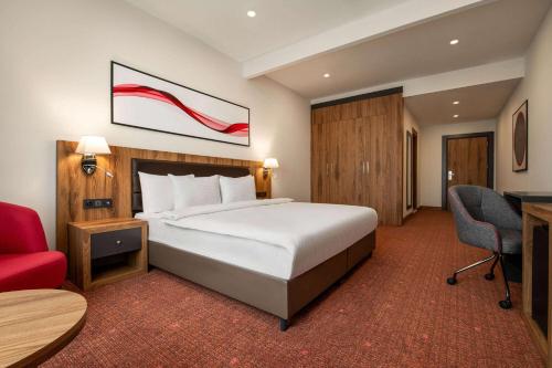 伯萨Ramada by Wyndham Karacabey的酒店客房,配有一张床和一张红色椅子