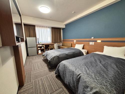 仓敷仓敷市1-2-3酒店的酒店客房设有两张床和蓝色的墙壁。