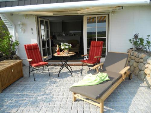 曼克玛肖Ferienwohnung für 2 Personen ca 55 qm in Munkmarsch, Nordfriesische Inseln Sylt的庭院配有两把椅子、一张桌子和一张桌子