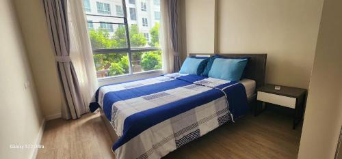 清迈An Na Park Hotel Room - Chiang Mai的一间卧室配有一张带蓝色枕头的床和一扇窗户。