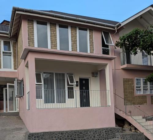 弗里敦Remarkable 3-Bed House in Freetown的粉红色的房子 - 带阳台
