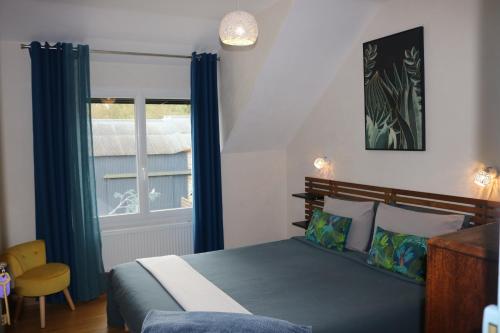 FaverollesL'autre Monde的一间卧室配有一张带蓝色窗帘的床和一扇窗户