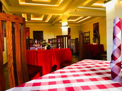 阿鲁沙Kerama Silent Lodge的一间设有两张桌子的房间,配有红色和白色的桌布