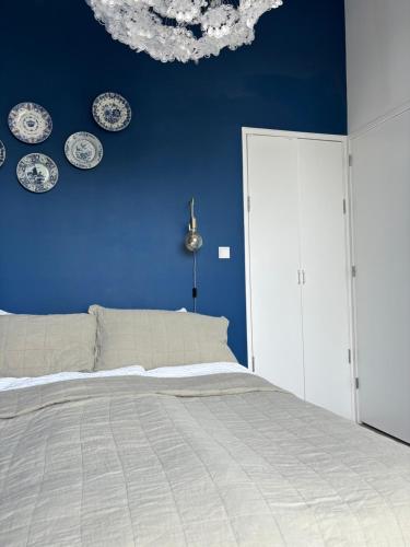 阿姆斯特丹Lovely small apartment in 'De Pijp'的蓝色卧室,墙上挂有床和盘子