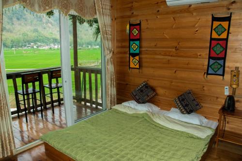 枚州县Mai Chau La Vida Homestay的一间卧室设有一张床和一个大窗户