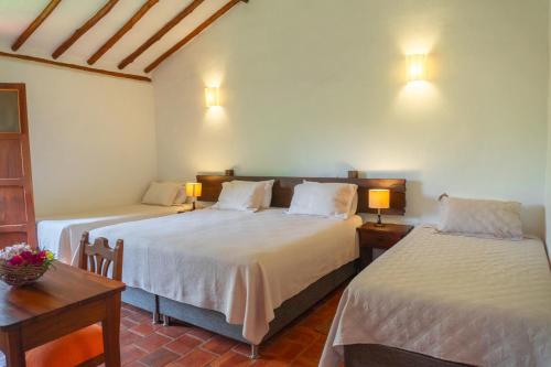 巴里查拉Hotel Hacienda Macedonia的一间卧室配有两张床、一张桌子和两盏灯。