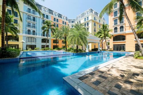 富国Pacific Apartment & Hotel Phu Quoc的一座棕榈树和建筑的大型游泳池
