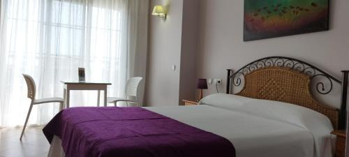 托雷德尔马尔米拉亚海滩酒店的一间卧室配有一张带紫色毯子的床