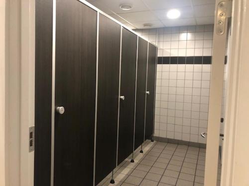 帕兹堡Motel eat´n drive Padborg的一间有黑色门的浴室里的一排摊位