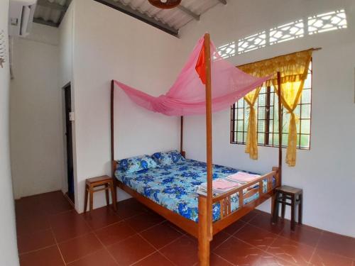 永隆幸福家庭旅馆的一间卧室配有一张带粉红色遮阳伞的床