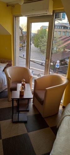 KuršumlijaApartmani Ad fines的一间设有两把椅子、一张桌子和一个窗户的房间