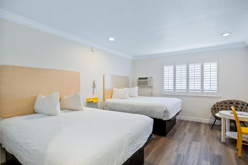 滨海城Gateway Lodge的一间卧室设有两张床、一张桌子和一个窗口