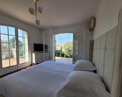 胡安莱潘Juan les pins : Villa de charme avec piscine的一间卧室设有一张大床和大窗户