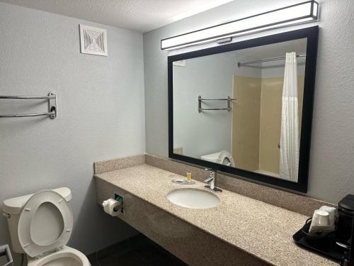 亚历山德里亚Super 8 by Wyndham Alexandria LA的浴室设有卫生间和带镜子的盥洗盆