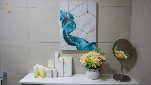 阿布扎比Chalet 2BR Duplex Apartment的浴室设有镜子和花卉,位于柜台上