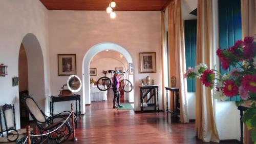 里奥迪孔塔斯Pousada Rio de Contas的站在走廊上,在房间里骑着自行车的人