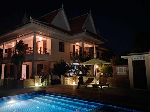 Phumĭ Kâmpóng ÂmpĭlLa maison bleue BTB的一座晚上设有游泳池的房子