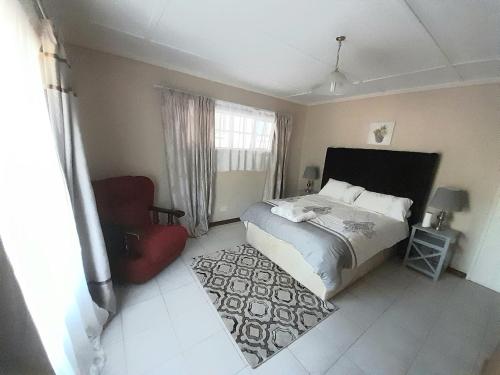 布拉瓦约The Villa的一间卧室配有一张床和一张红色椅子