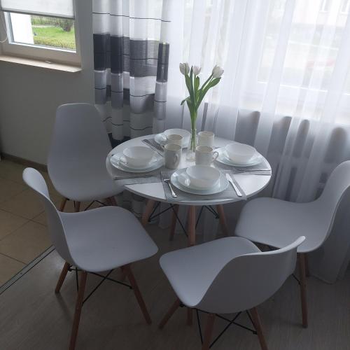 肯琴Apartament Mazurska的白色的桌子、白色的椅子和花瓶