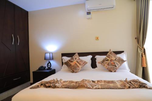 坎帕拉Precious Villas Lubowa的一间卧室配有带枕头的床