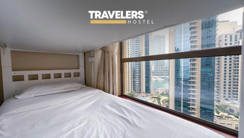 迪拜Travelers - Dubai Marina Hostel的一间卧室设有一张床和一个大窗户