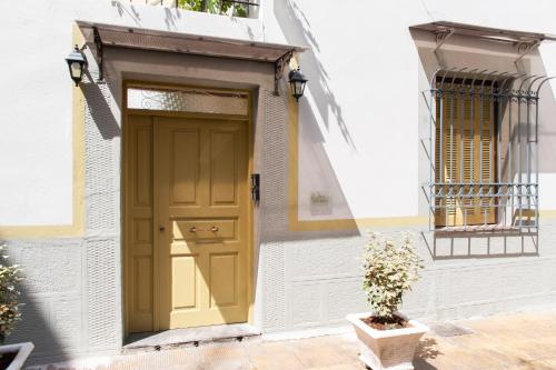 雅典17 flats and Roof Garden的白色建筑中一扇黄色的门,上面有盆栽植物