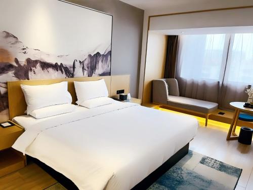 上海途客酒店（上海虹桥枢纽延安西路店）的卧室配有一张白色大床和一把椅子