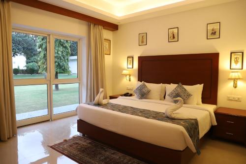 克久拉霍Hotel Chandela Khajuraho的一间卧室设有一张大床和一个大窗户