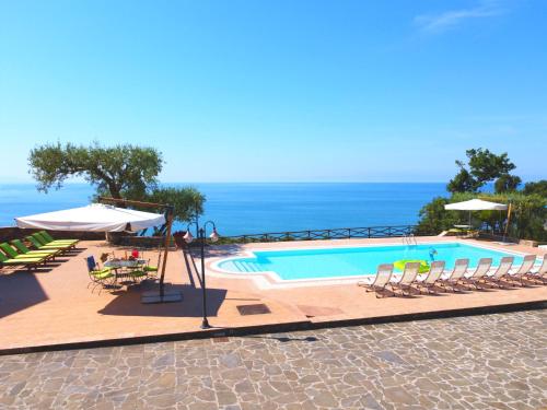 韦兰迈尔Villa Le Cannicelle的一个带椅子和遮阳伞的游泳池以及大海