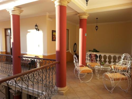 苏克雷Villa Oropeza Hostel的大堂设有红色柱子和桌椅