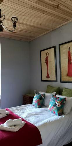 帕特森The Wild Olive Sanctuary Accommodation的卧室配有一张白色床,墙上挂有绘画作品