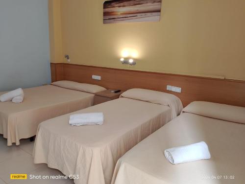 塞古德卡拉斐Hotel Sant Jordi的带3张白色床单的床的房间