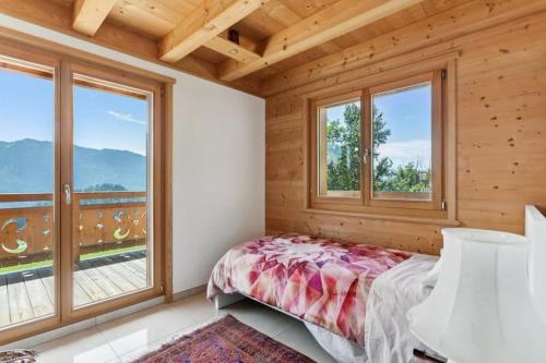 莱森温特菲尔木屋的一间卧室设有一张床和大窗户