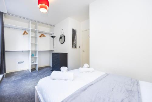 伦敦Modern 1 BR Apartment Near Shoreditch - 10 Min Walk的一间白色卧室,配有两张床和黑色梳妆台