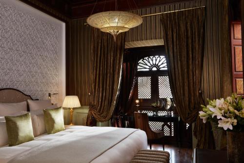 马拉喀什皇家曼苏尔马​​拉喀什酒店的一间卧室配有一张大床和一个吊灯。