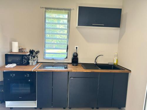 马罗尼河畔圣洛朗JEALYA TOURISTIQUES的厨房配有蓝色橱柜、水槽和窗户。