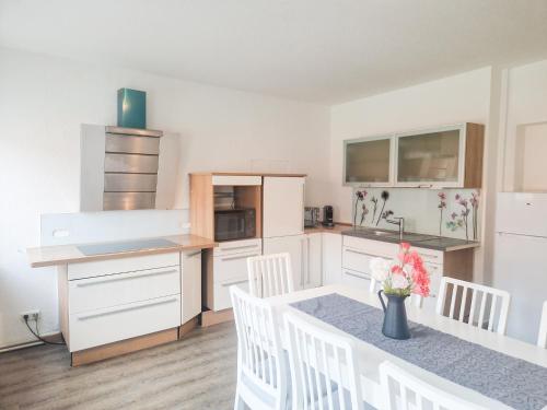 希尔德斯海姆Apartment am Dammtor的厨房配有白色橱柜和一张带白色椅子的桌子