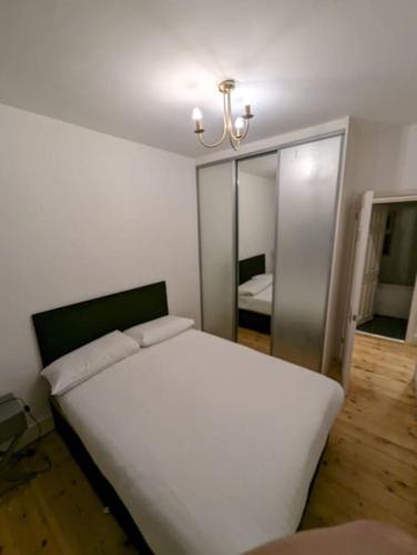 布伦特伍德Cozy 2 Beds Brentwood Flat的卧室配有白色的床和镜子