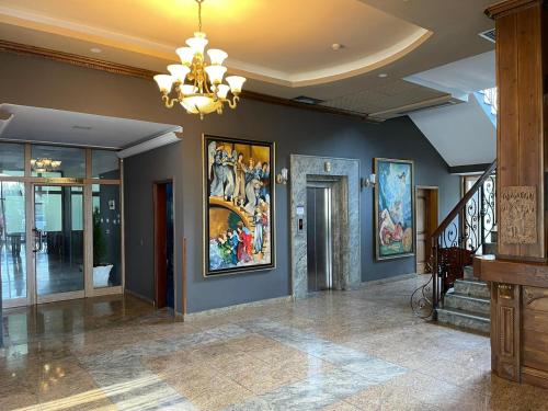 地拉那Misk Hotel & Resort的大堂设有吊灯,墙上挂有绘画作品