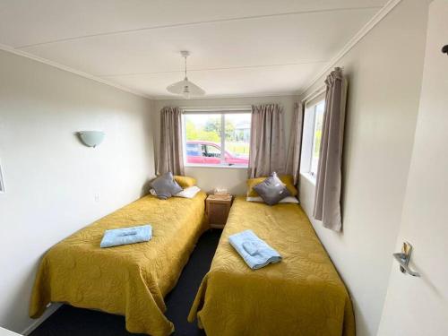 PoharaPohara's Seaside Chalet的配有黄色床单的客房内的两张床