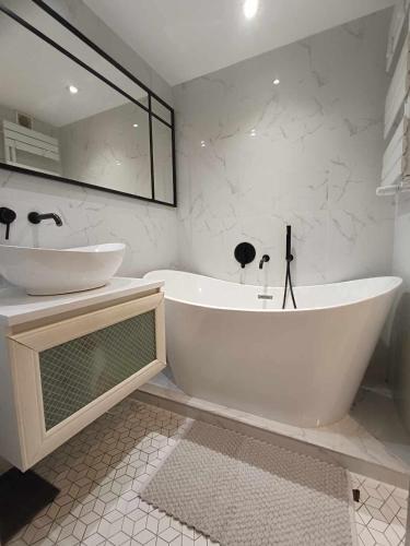 罗兹DWUPOKOJOWY APARTAMENT 51 m2的白色的浴室设有浴缸和水槽。