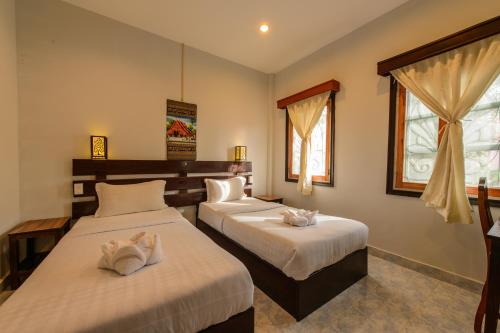 琅勃拉邦萨拜迪旅馆的一间卧室配有两张带毛巾的床