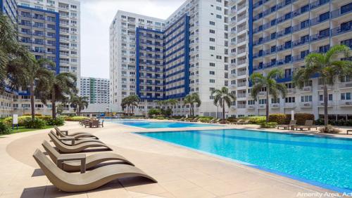 马尼拉SEA Residences in Pasay near Mall of Asia 2BR and 1BR的一座带躺椅的游泳池,位于高楼前