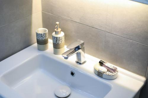 伏罗拉Guest House Narta的浴室水槽,上面装有水龙头和杯子