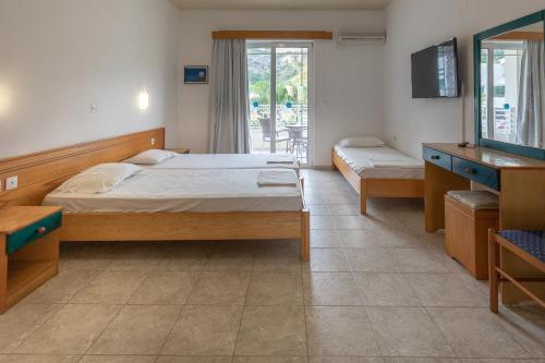 罗德岛卡利地亚Faliraki Dream Apartments & Studios的一间卧室配有两张床、一台电视和镜子
