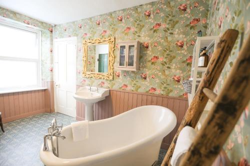 林茅斯Ferndale Cottage的浴室配有浴缸和水槽,拥有花卉图案的壁纸