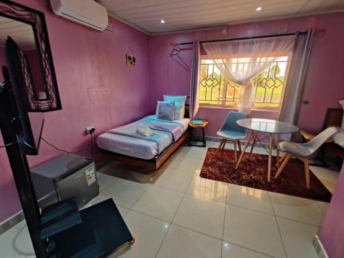 MpongweBukari Executive Lodge的客房设有床、桌子和窗户。