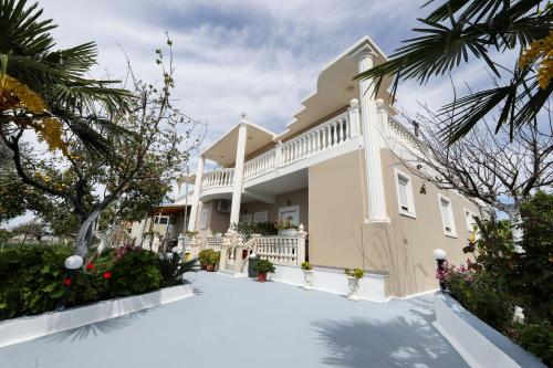 伏罗拉Guest House Narta的带阳台和树木的大型白色房屋